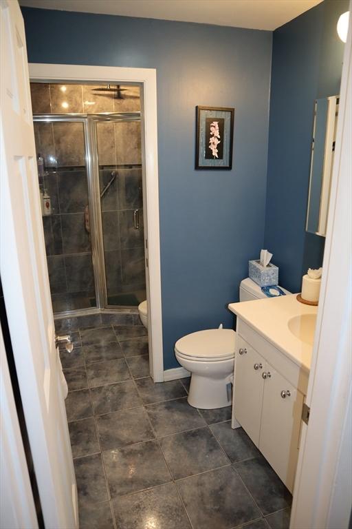 bathroom featuring vanity, an enclosed shower, and toilet