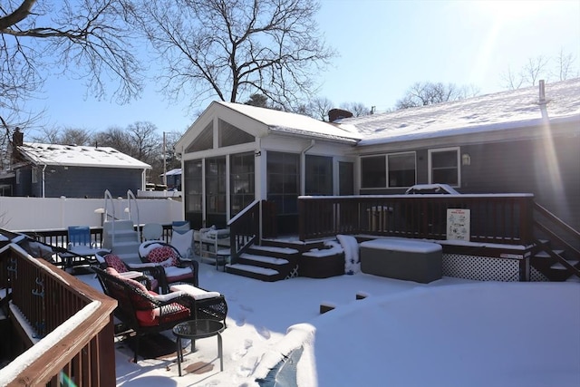 snow covered back of property featuring a sunroom