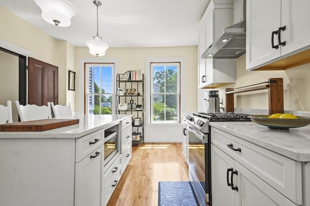 33 Grove St, Merrimac, MA 01860 - kitchen with wall chimney range hood, appliances with stainless steel finishes, light wood-style floors, pendant lighting, and white cabinetry