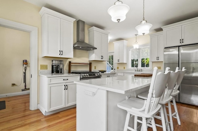 33 Grove St, Merrimac, MA 01860 - kitchen featuring wall chimney range hood, stainless steel appliances, white cabinets, and a kitchen bar