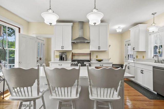 33 Grove St, Merrimac, MA 01860 - kitchen featuring wall chimney range hood, appliances with stainless steel finishes, light countertops, and a breakfast bar