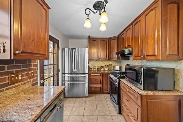 kitchen with decorative backsplash, light stone counters, light tile patterned floors, and stainless steel appliances