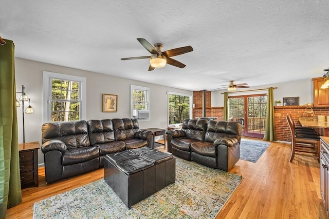 living room featuring ceiling fan, light hardwood / wood-style flooring, cooling unit, and a textured ceiling