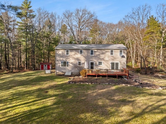 rear view of property featuring a shed, a deck, and a yard