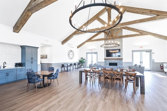 13 Birkdale Ln Unit 13, Hopkinton, MA 01748 - dining area with wainscoting, beam ceiling, a fireplace, high vaulted ceiling, and light wood-type flooring