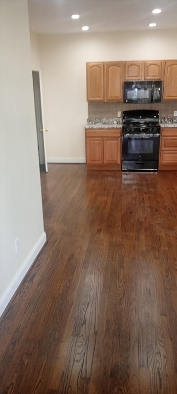 kitchen featuring dark wood-type flooring, tasteful backsplash, black appliances, and light brown cabinets