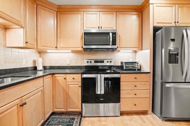 kitchen with backsplash, appliances with stainless steel finishes, and light brown cabinetry