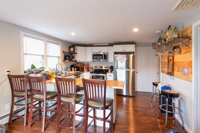 kitchen featuring white cabinetry, appliances with stainless steel finishes, a breakfast bar area, and kitchen peninsula