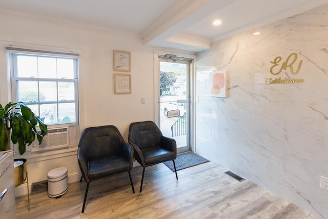 living area with cooling unit, plenty of natural light, ornamental molding, and light wood-type flooring