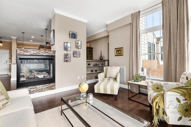 living room with ornamental molding, wood finished floors, a multi sided fireplace, and baseboards