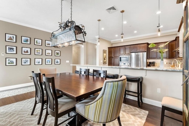 dining room featuring baseboards, visible vents, crown molding, and wood finished floors