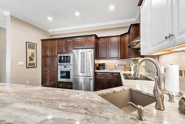 kitchen with tasteful backsplash, wall chimney exhaust hood, light stone counters, stainless steel appliances, and crown molding