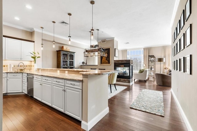 kitchen featuring visible vents, open floor plan, a peninsula, white cabinetry, and pendant lighting