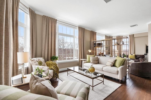 living area featuring a wealth of natural light, dark wood-style flooring, and visible vents