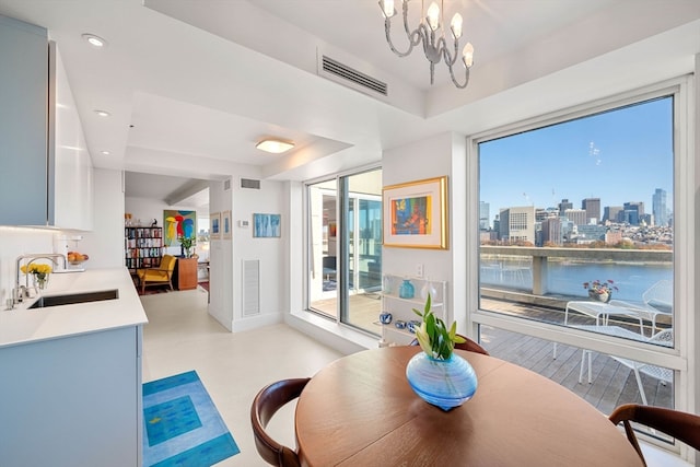 dining space with an inviting chandelier, a water view, and sink