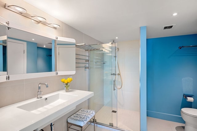 bathroom with toilet, tile patterned flooring, sink, backsplash, and a shower with shower door