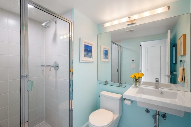 bathroom featuring toilet, sink, and a shower with door