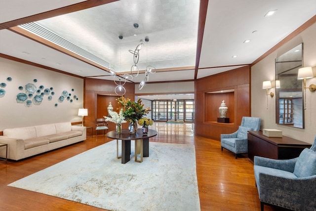 living room with wood-type flooring, an inviting chandelier, and crown molding