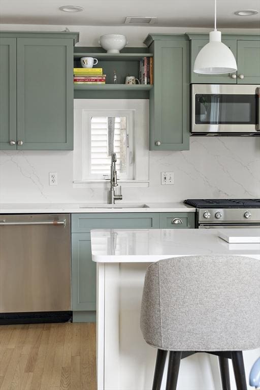 414 Sumner St Unit 1, Boston, MA 02128 - kitchen with appliances with stainless steel finishes, green cabinetry, a sink, and backsplash