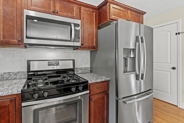 43 Julian Dr, Leominster, MA 01453 - kitchen featuring stainless steel appliances, light wood-style floors, tasteful backsplash, and brown cabinetry