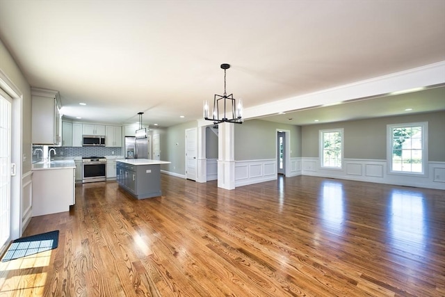 526 Old Warren Rd, Swansea, MA 02777 - unfurnished living room featuring a chandelier, wood finished floors, wainscoting, recessed lighting, and a decorative wall