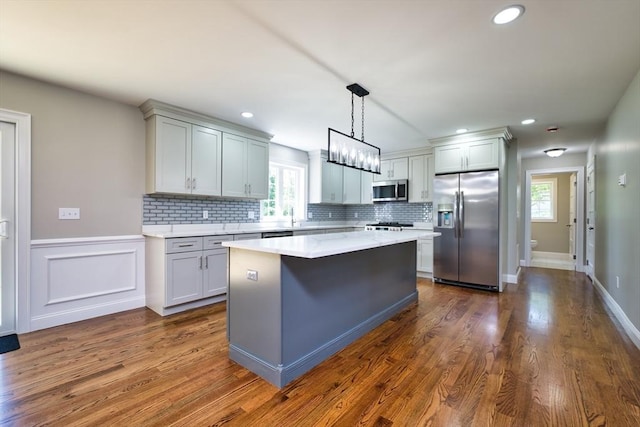 526 Old Warren Rd, Swansea, MA 02777 - kitchen with stainless steel appliances, light countertops, backsplash, a kitchen island, and dark wood-style flooring