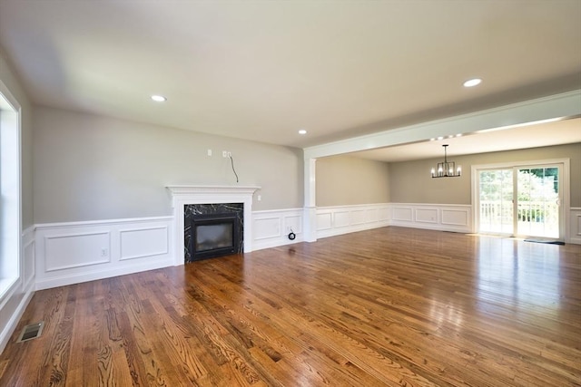 526 Old Warren Rd, Swansea, MA 02777 - unfurnished living room with a premium fireplace, a chandelier, a decorative wall, a wainscoted wall, and wood finished floors