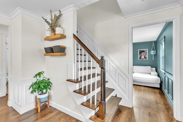 staircase with ornamental molding and hardwood / wood-style floors