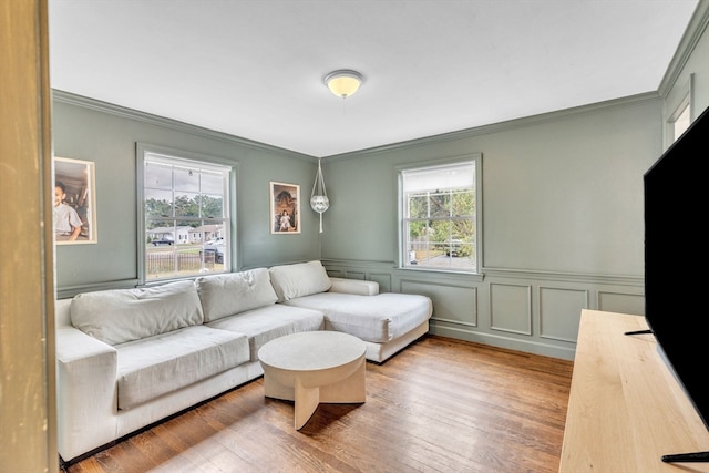 living room featuring wood-type flooring, crown molding, and a healthy amount of sunlight