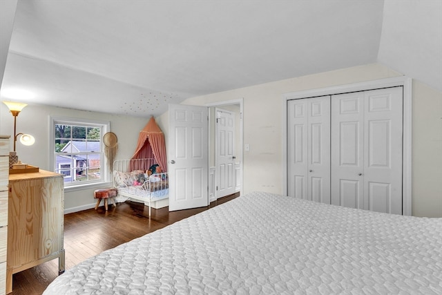 bedroom featuring vaulted ceiling, a closet, and dark hardwood / wood-style flooring