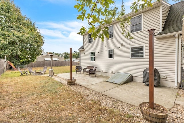 back of property with a patio, a lawn, and an outdoor fire pit