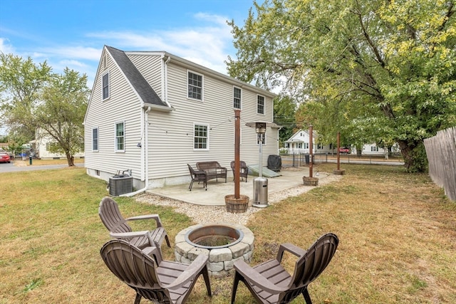 rear view of property featuring central AC unit, a fire pit, a lawn, and a patio area