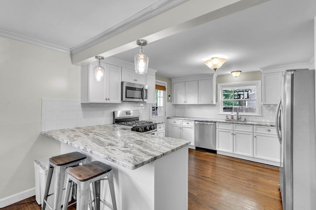 kitchen with pendant lighting, kitchen peninsula, white cabinetry, appliances with stainless steel finishes, and a breakfast bar