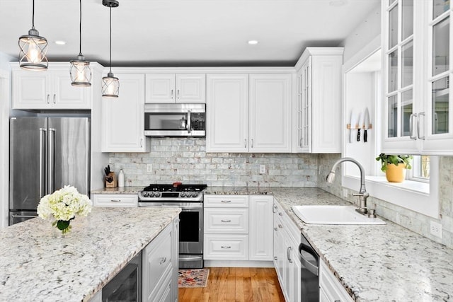 kitchen featuring hanging light fixtures, a sink, stainless steel appliances, white cabinetry, and wine cooler