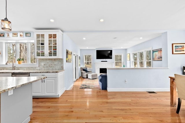 kitchen with white cabinetry, a healthy amount of sunlight, a sink, and light wood finished floors