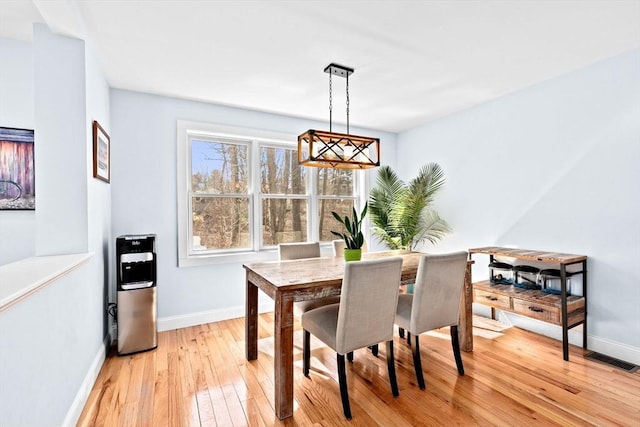 dining area featuring an inviting chandelier, baseboards, light wood finished floors, and visible vents