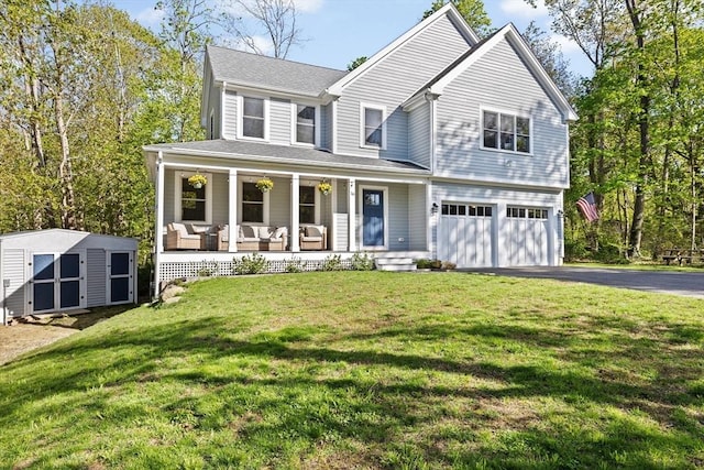 view of front of property with a garage, driveway, a front yard, a porch, and a storage shed