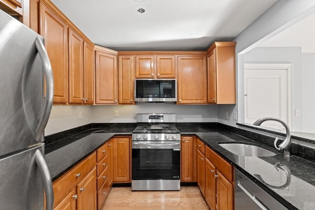 kitchen with appliances with stainless steel finishes, sink, and dark stone countertops