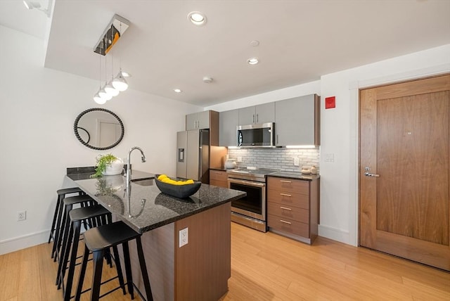 45 Province St Unit 1103, Boston, MA 02108 - kitchen with stainless steel appliances, a kitchen breakfast bar, tasteful backsplash, light wood finished floors, and a sink
