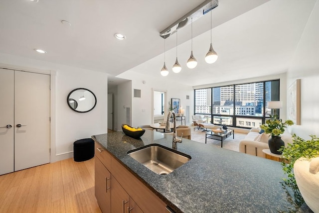 45 Province St Unit 1103, Boston, MA 02108 - kitchen featuring a sink, open floor plan, decorative light fixtures, dark stone countertops, and light wood-style floors