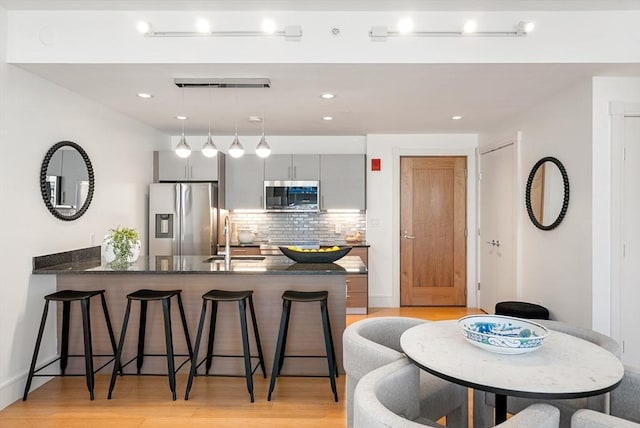 45 Province St Unit 1103, Boston, MA 02108 - kitchen featuring appliances with stainless steel finishes, a breakfast bar area, a peninsula, decorative backsplash, and a sink