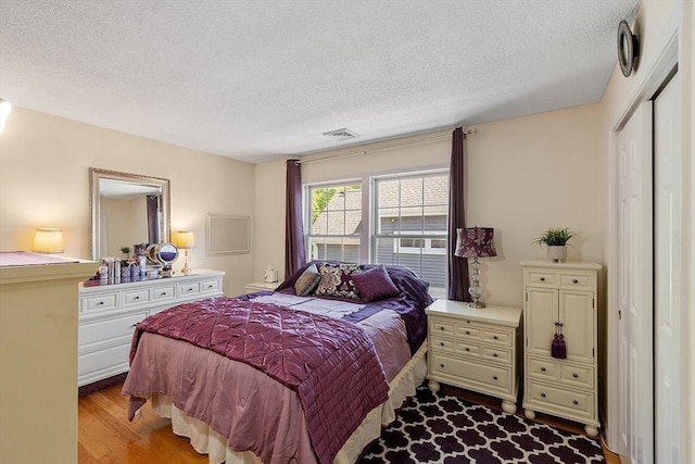 bedroom with a textured ceiling and wood finished floors