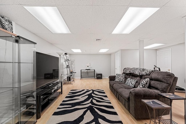 living room featuring light wood-type flooring and a paneled ceiling