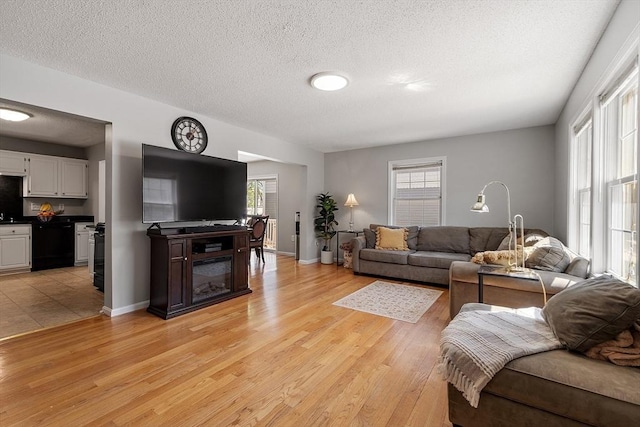 living area with light wood finished floors, a textured ceiling, and baseboards