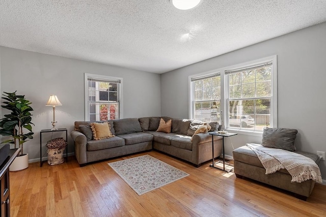 living area with a textured ceiling, light wood-type flooring, and baseboards