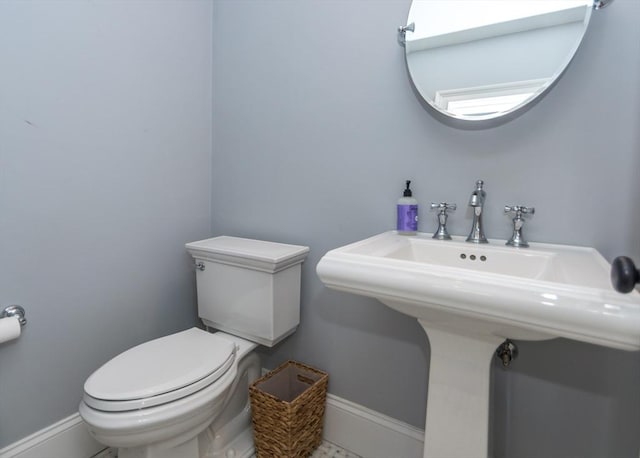 half bath featuring toilet and baseboards