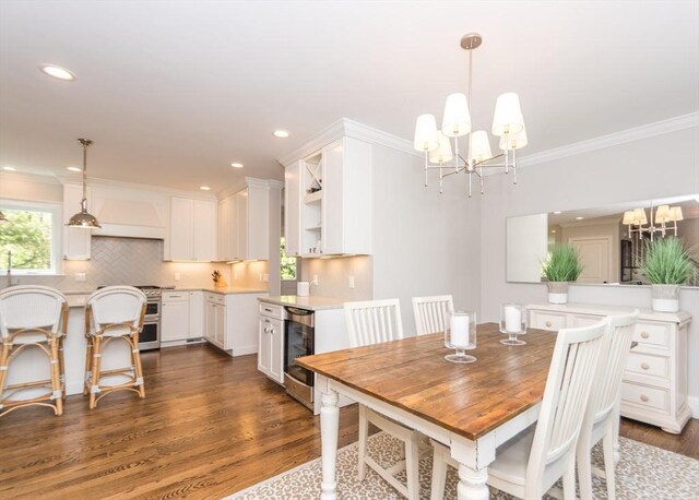 dining space with wine cooler, a chandelier, dark wood-style floors, ornamental molding, and recessed lighting