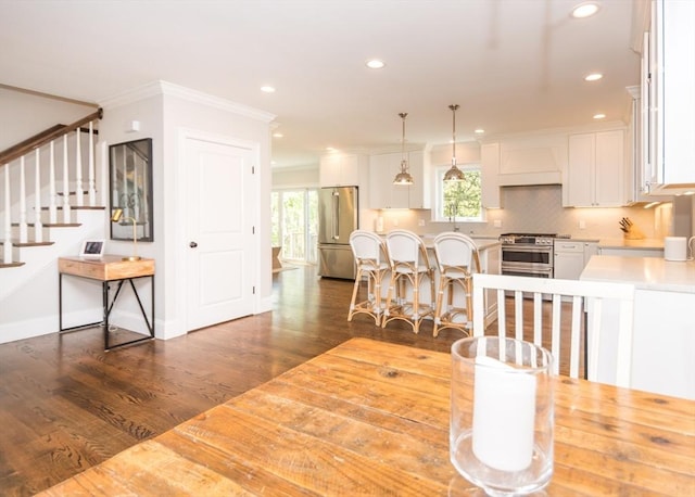 dining area featuring ornamental molding, plenty of natural light, dark wood-style floors, stairs, and recessed lighting