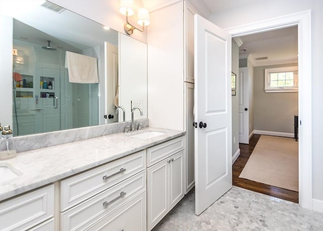 full bathroom featuring a stall shower, ornamental molding, double vanity, and baseboards