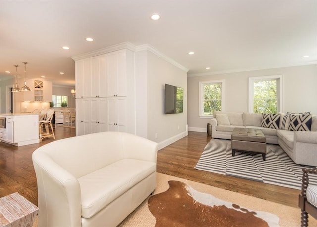 living area featuring recessed lighting, plenty of natural light, ornamental molding, dark wood-style flooring, and baseboards